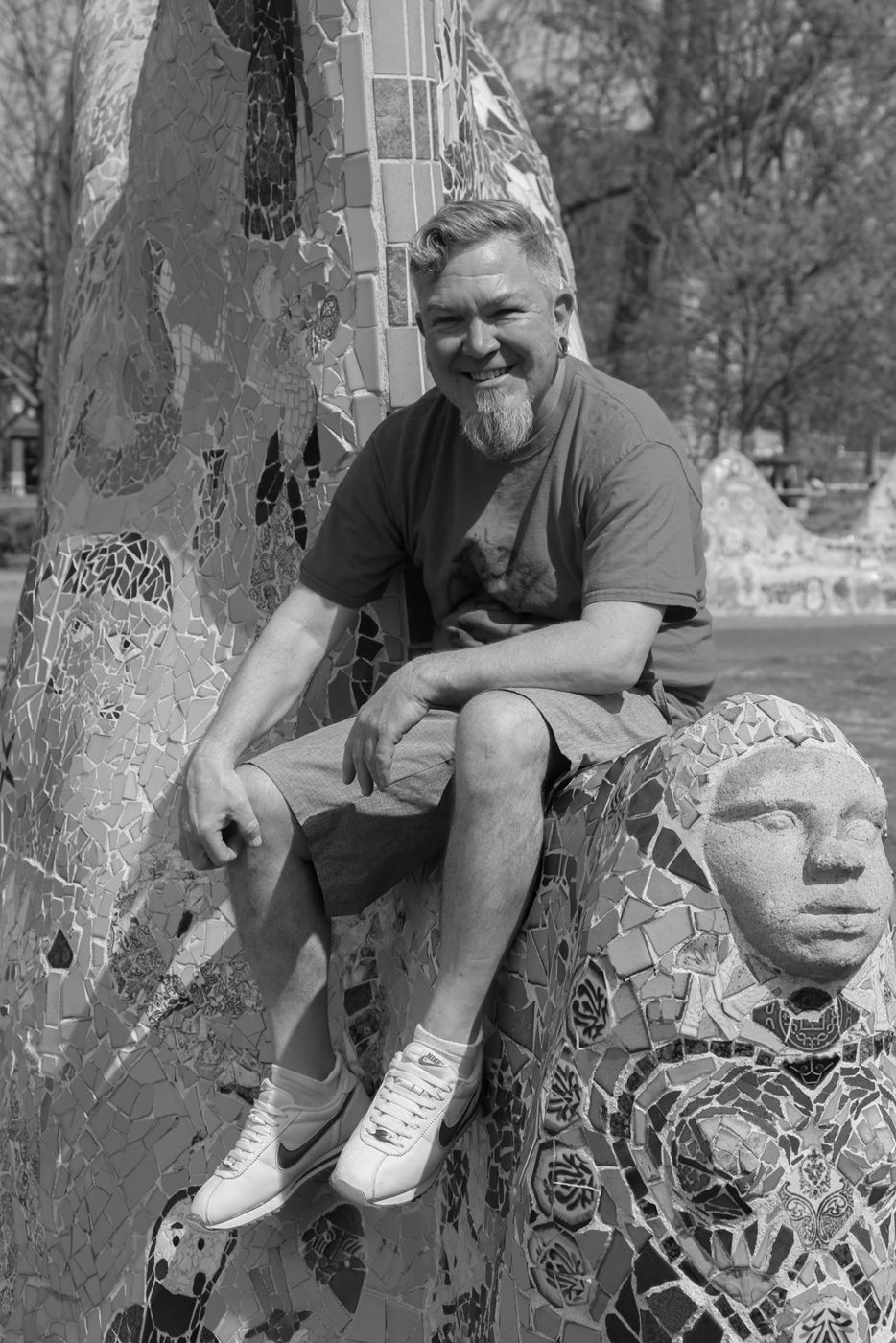 Mighty Rock smiling, seated on a mosaic sculpture